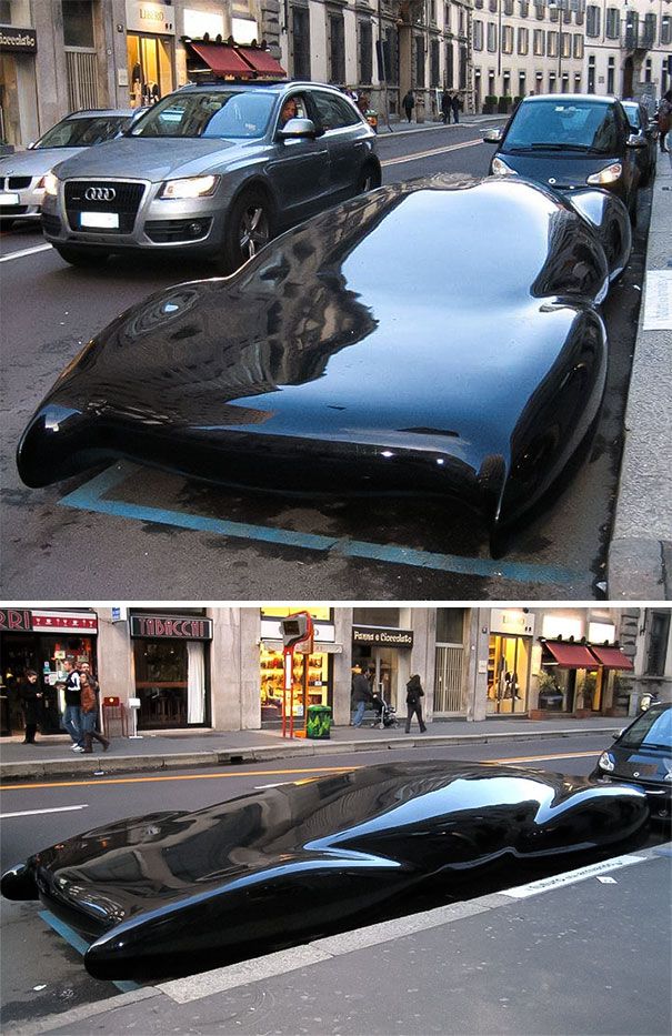 an unusual car is parked on the side of the road in front of some buildings