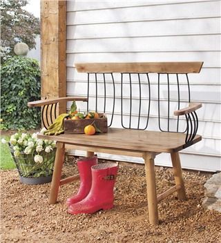 a wooden bench sitting in front of a white house with a red boot on it