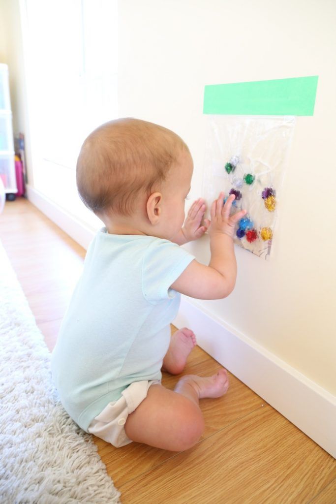 a baby sitting on the floor playing with magnets and paper clips in front of a wall