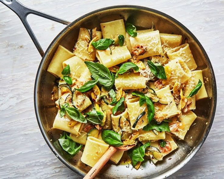 a pan filled with pasta and spinach on top of a table