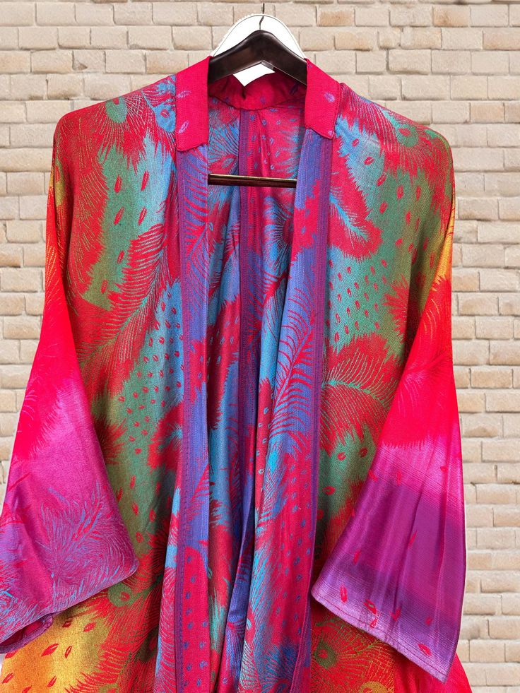 Say goodbye to scarves and hello to our luxurious kimonos. The rainbow peacock feather prints add a touch of bohemian flair, while the cozy fabric keeps you warm and comfortable. The free-size kimono offers a fashionable solution for anyone conscious about style and comfort. Perfect for any occasion. ~~Item details~~ Handmade from a delightful and soft pashmina fabric. Features a bohemian style oversized and flowing design. Styled like a cardigan with an open front and generous sleeves . The fro Bohemian Multicolor Silk Kimono, Multicolor Silk Kimono For Fall, Bohemian Red Silk Kimono, Festive Multicolor Silk Kimono, Traditional Multicolor Summer Outerwear, Winter Festival Multicolor Kimono, Rainbow Peacock, Festival Kimono, Bohemian Mini Dress