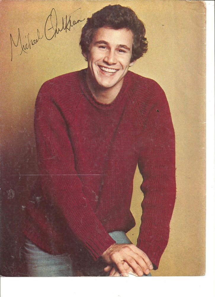 an old photo of a smiling man in a red sweater with his hands on his hips