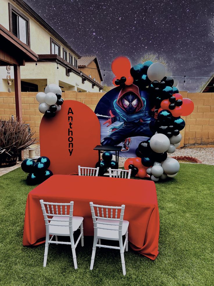 a table and chairs are set up in the grass for an outdoor party with balloons