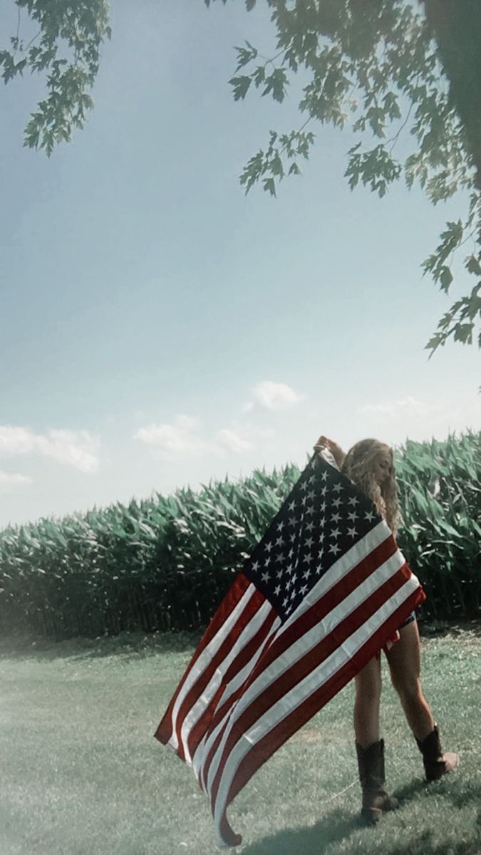 a person holding an american flag in the grass