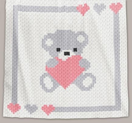 a crocheted baby blanket with a teddy bear holding a heart in the middle