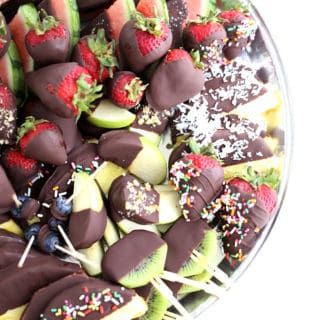 chocolate covered fruit arranged in a bowl with sprinkles and strawberries