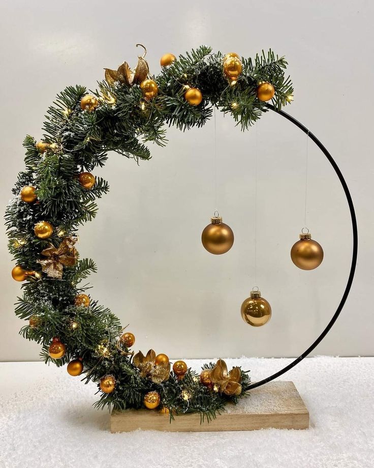 a circular christmas wreath with ornaments hanging from it's sides on a wooden stand