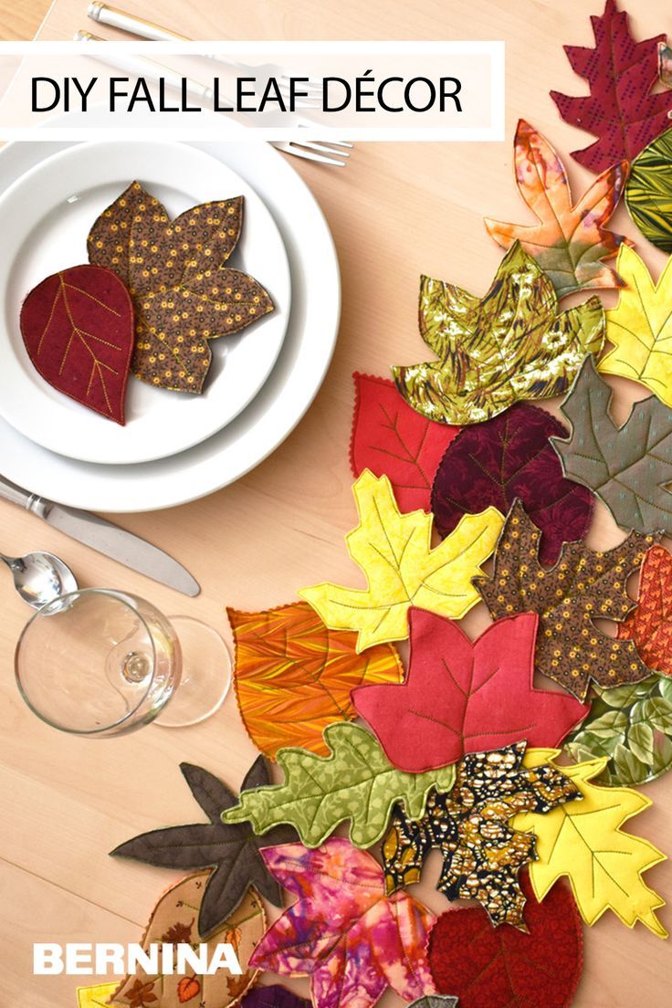 a table topped with plates and silverware covered in fall leaf napkins on top of a wooden table