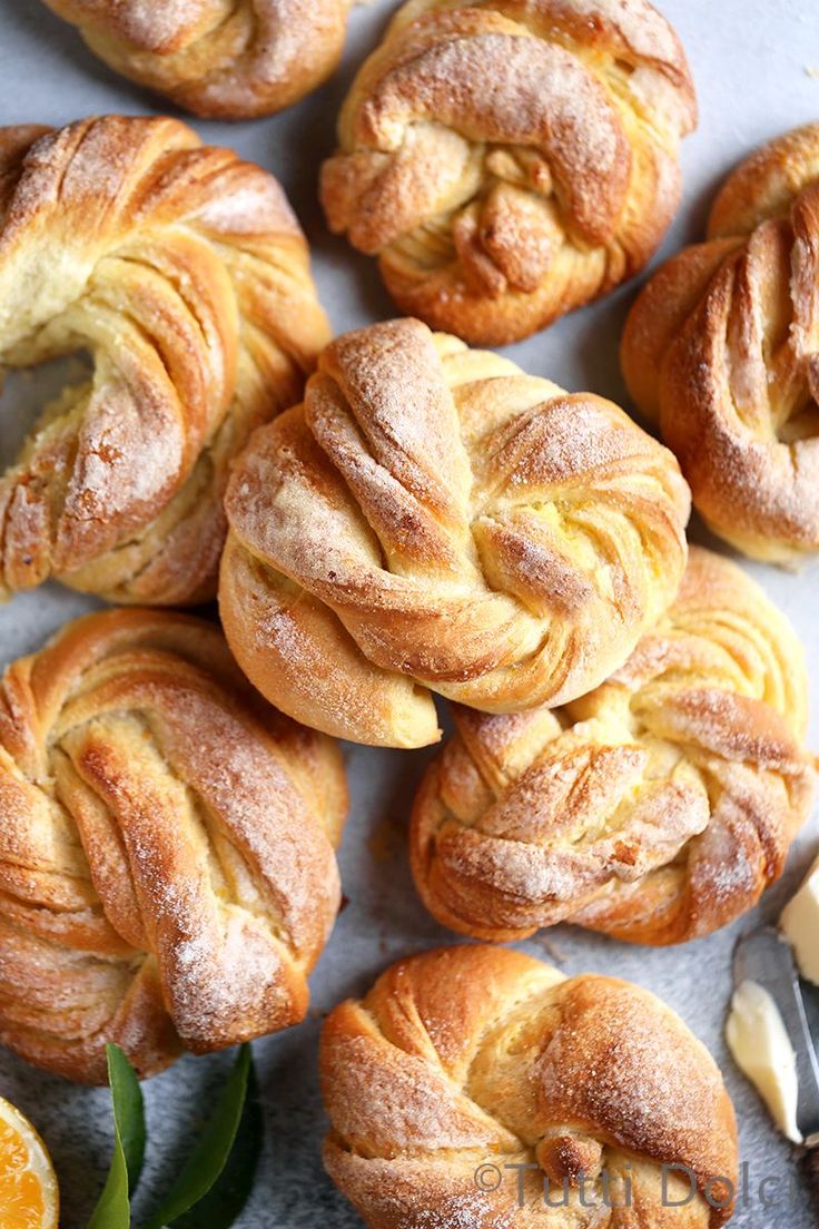 freshly baked croissants with powdered sugar and orange slices on the side