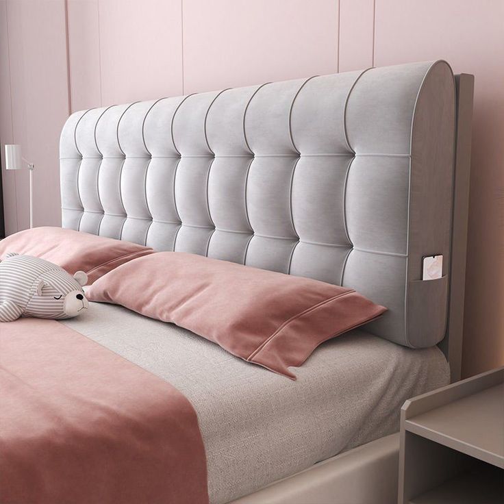 a bed with pink sheets and pillows in a room