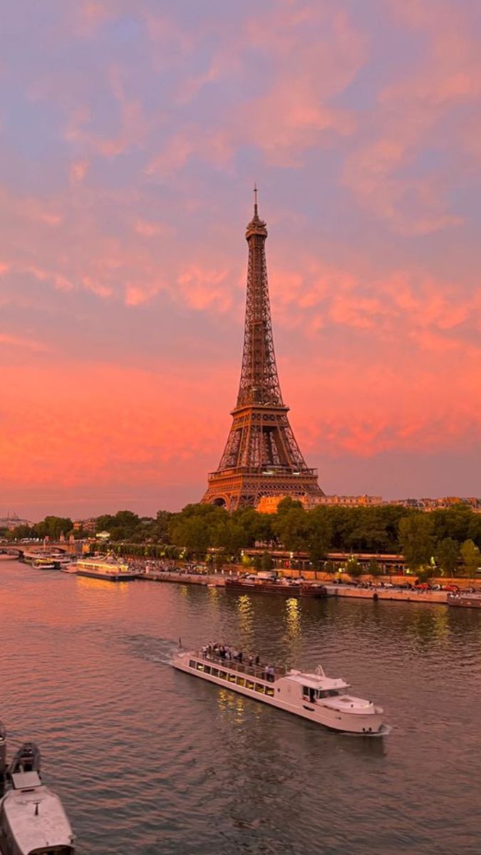 the eiffel tower towering over the city of paris at sunset with boats in the water