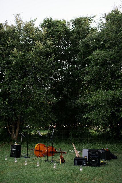 an outdoor concert setup in the middle of a grassy area with lights strung from trees