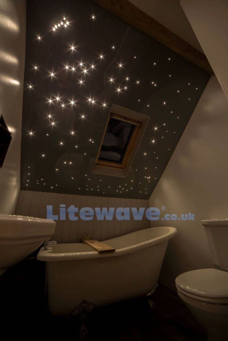 a white bath tub sitting next to a toilet under a bathroom ceiling with stars on it