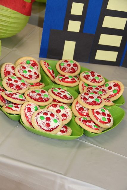 there are many cookies on the table with green plates and cups in the back ground