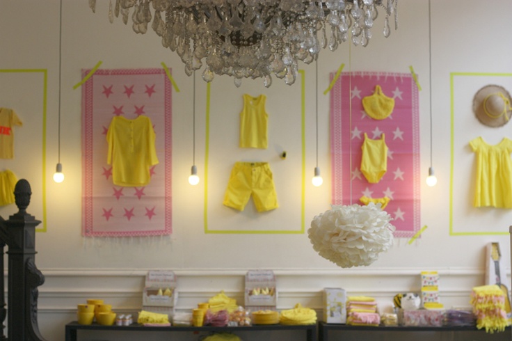 a room with yellow and pink clothes hanging on the wall next to a chandelier