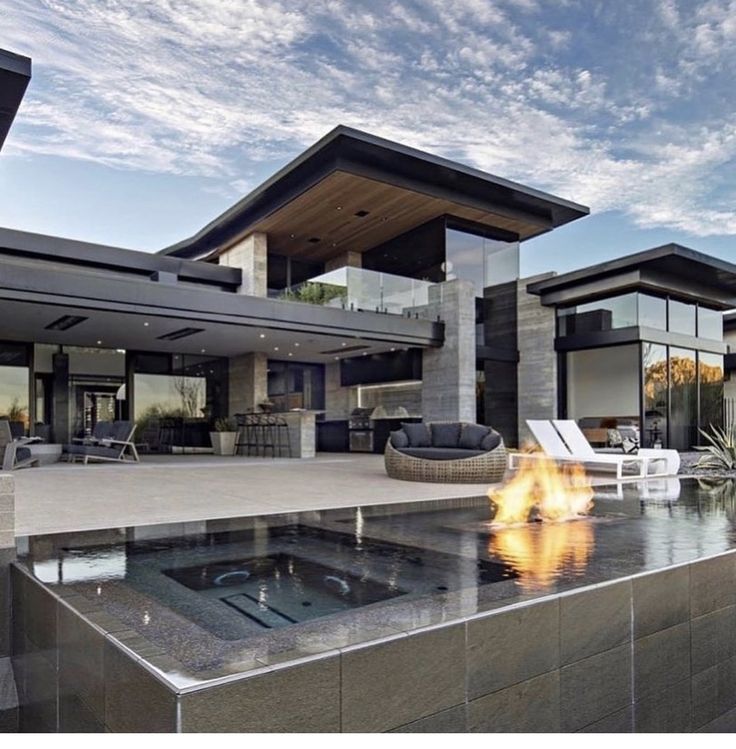 an outdoor fire pit in front of a modern house