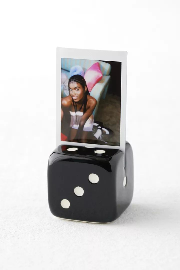 a black dice with two white dots sitting on it's side next to a photo of a woman