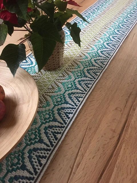 a table runner with flowers and fruit on it next to a vase filled with apples