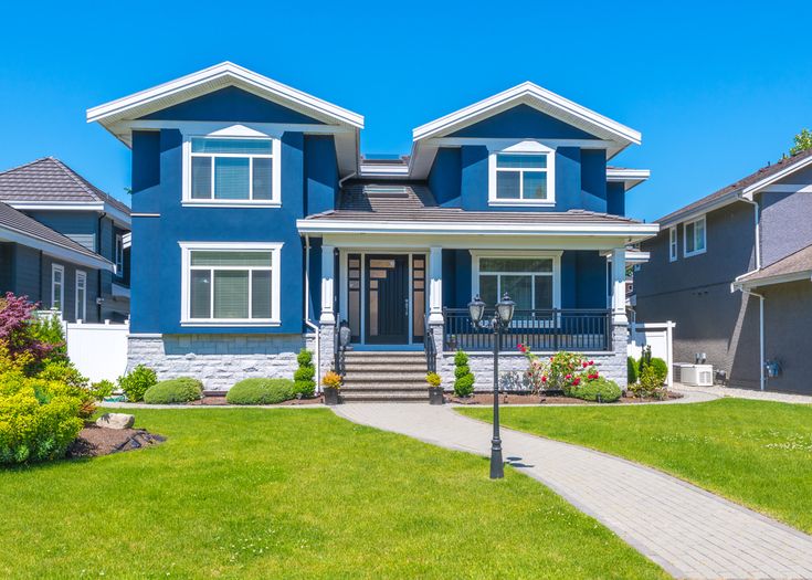 a blue house with white trim on the front and two story houses in the back