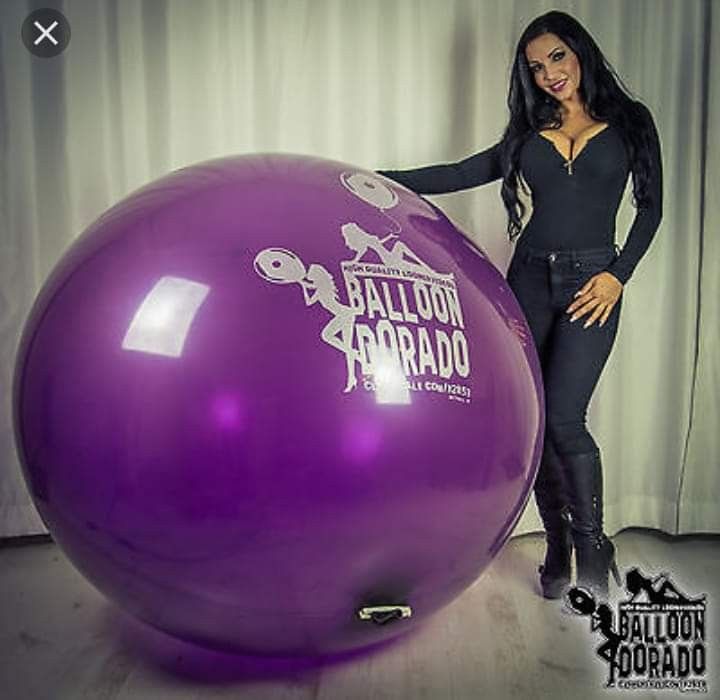 a woman standing next to a large purple ball