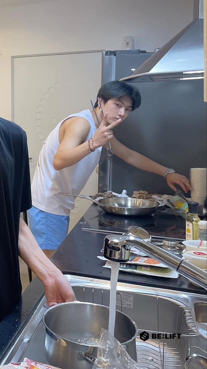 a man standing in front of a kitchen sink next to a pan filled with food