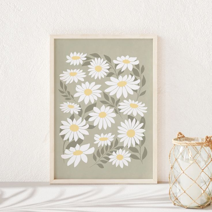 a white vase sitting on top of a table next to a framed flower art print