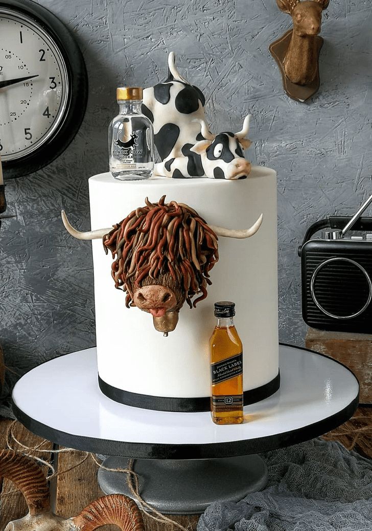 there is a cake with a cow on it and two bottles in front of it