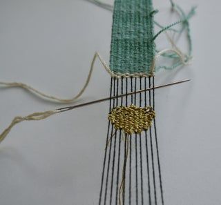 a close up of a piece of cloth with some knitting needles in front of it