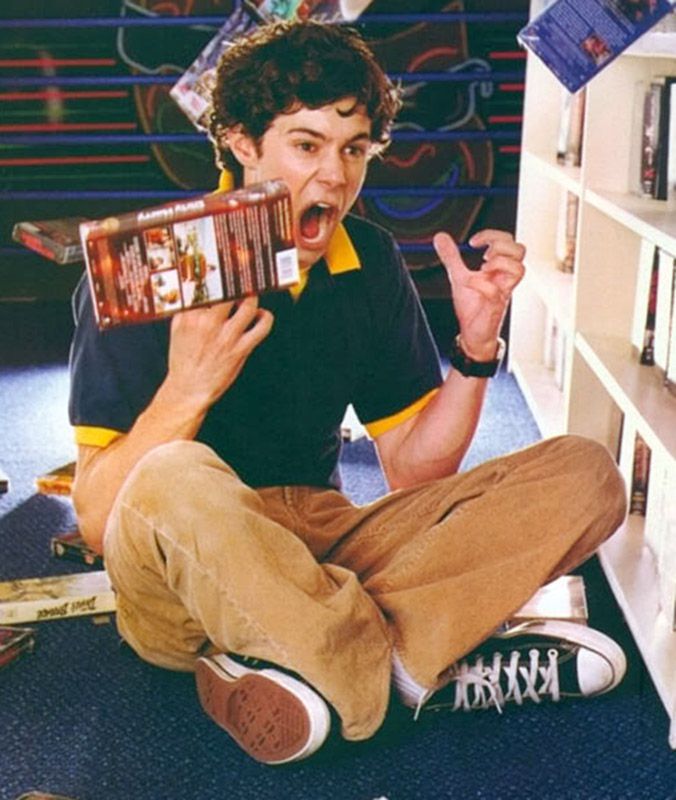 a young man sitting on the floor with his mouth open and holding an object in front of him