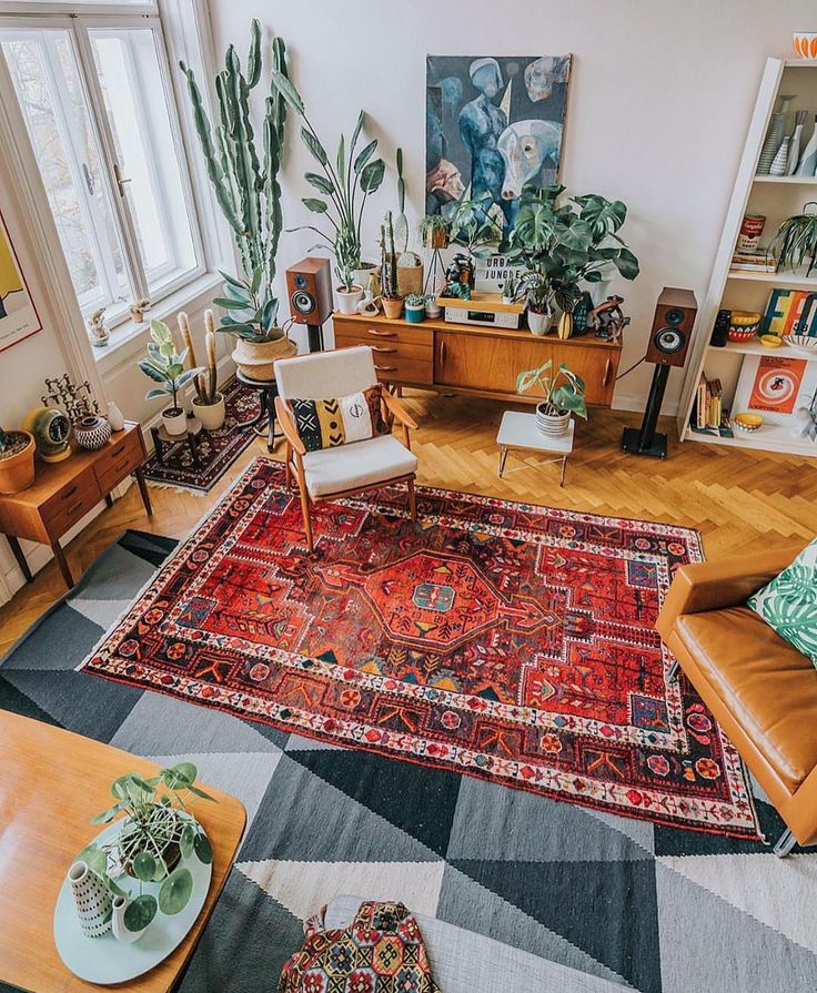 a living room filled with lots of furniture and plants on top of a large rug