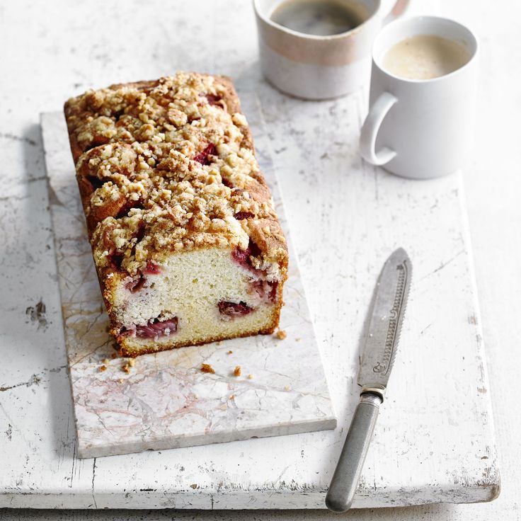 a piece of cake sitting on top of a cutting board next to a cup of coffee