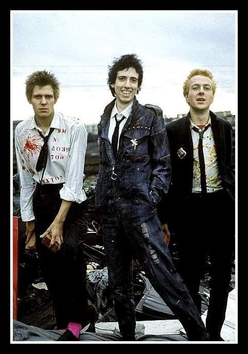 three young men standing next to each other on top of a pile of junk and debris