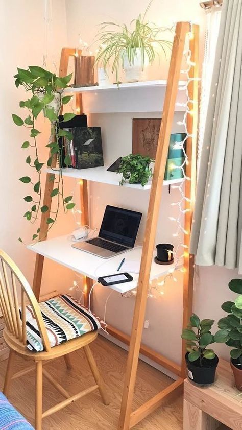 a laptop computer sitting on top of a white desk next to a wooden ladder filled with potted plants