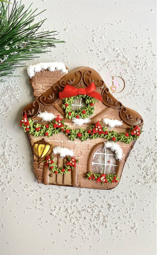 a gingerbread house ornament with holly wreaths