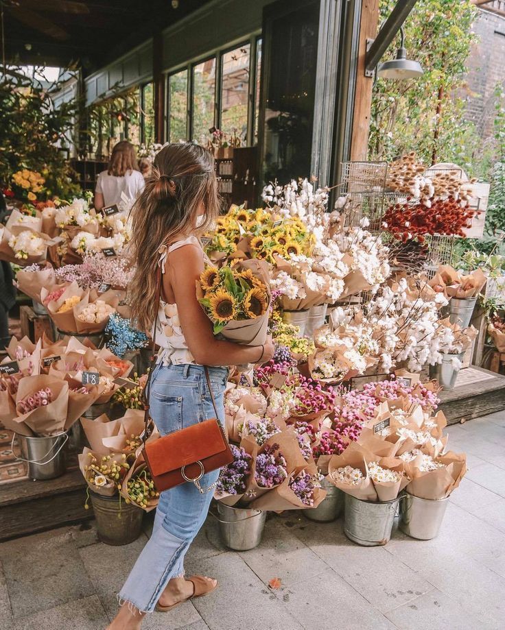 a woman standing in front of a flower shop