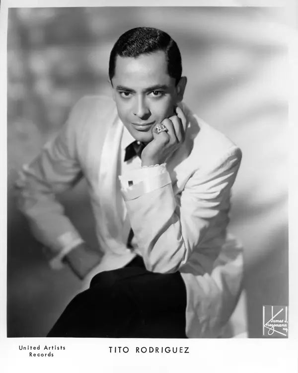 a black and white photo of a man in a tuxedo with his hand on his chin