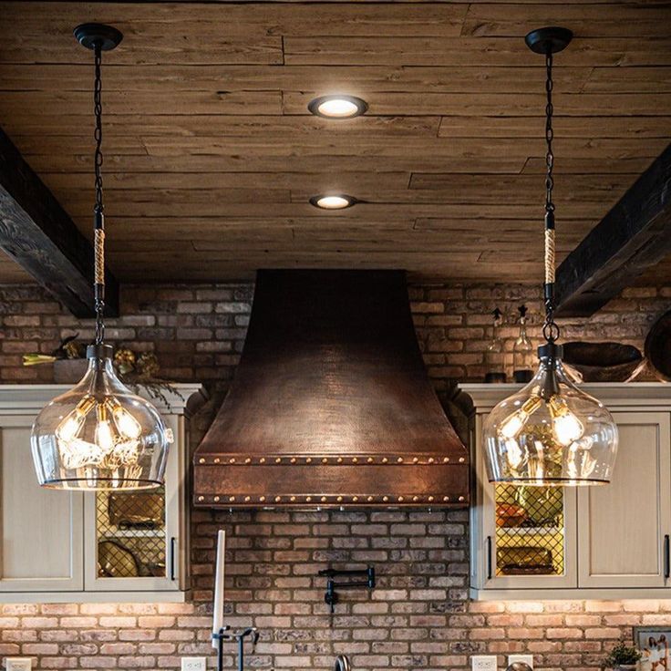 a kitchen with brick walls and two pendant lights hanging from the ceiling over the stove