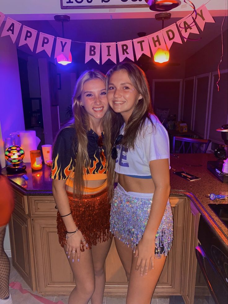 two girls standing next to each other in front of a birthday sign