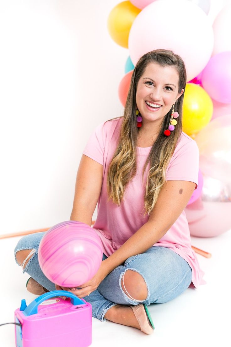 a woman sitting on the floor with balloons and a pink ball in front of her