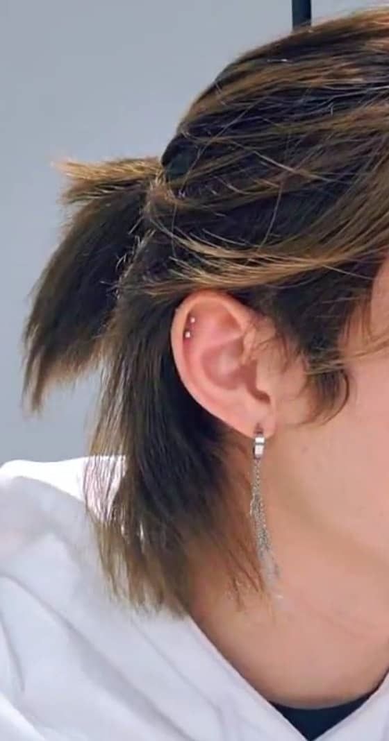 a close up of a person wearing earring's and a white hoodie