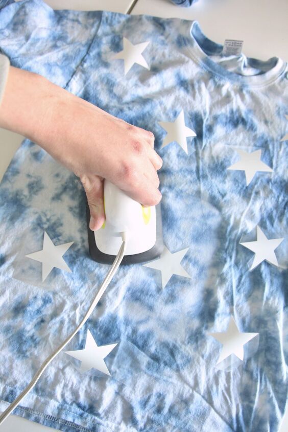 a person using an ironing board to sew stars on a t - shirt