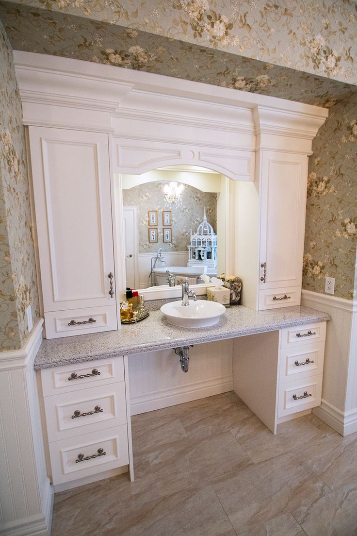 a large bathroom with white cabinets and marble counter tops, along with wallpapered walls