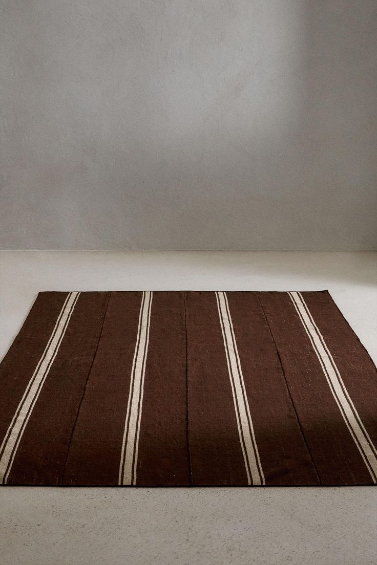 a brown and white striped rug sitting on top of a floor next to a wall