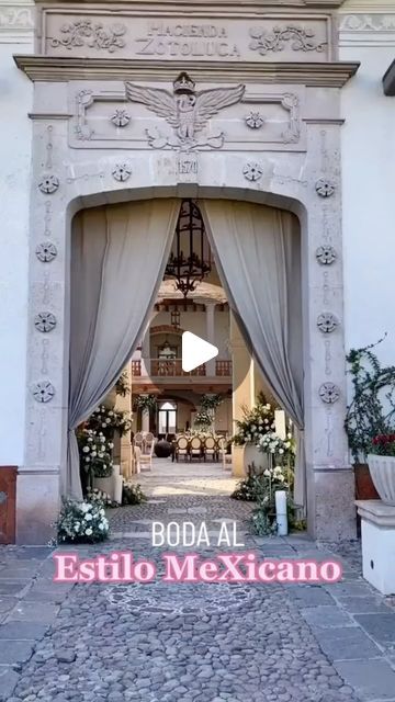 an entrance to a building with white curtains and flowers on the front door is shown