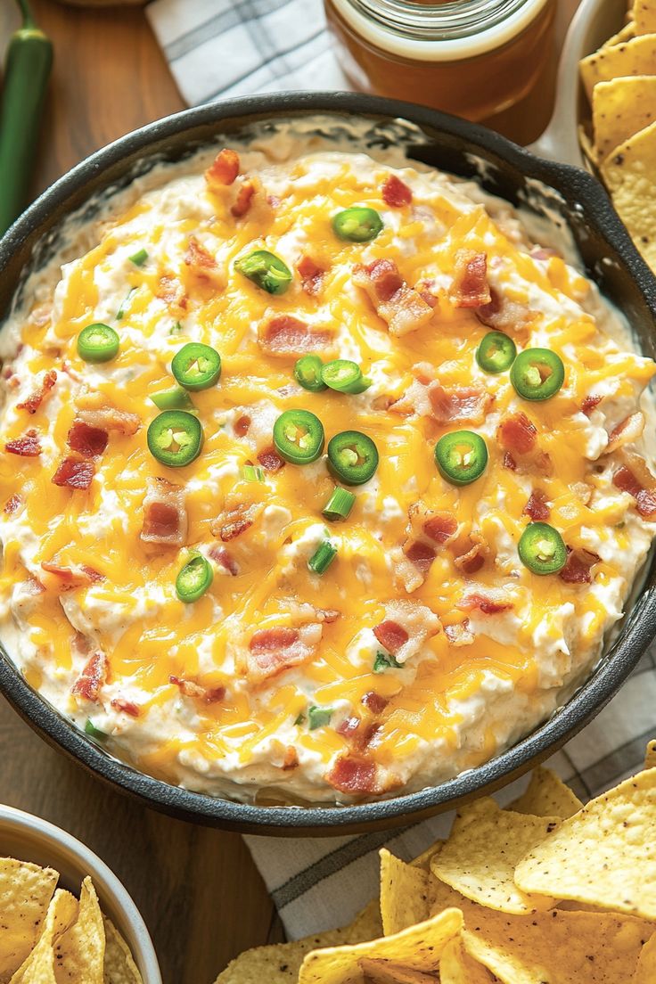 an image of a bowl of dip with cheese and jalapenos on the side