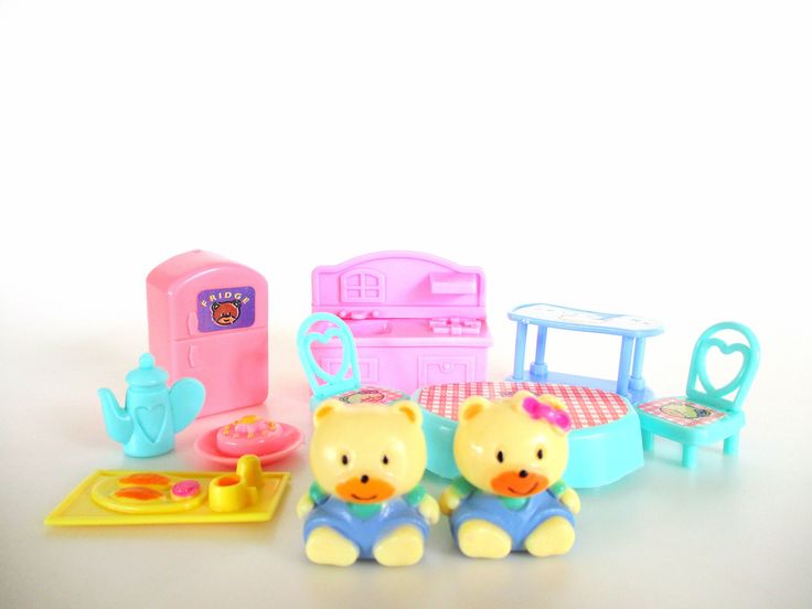 there are two toy bears sitting next to each other in front of a play kitchen