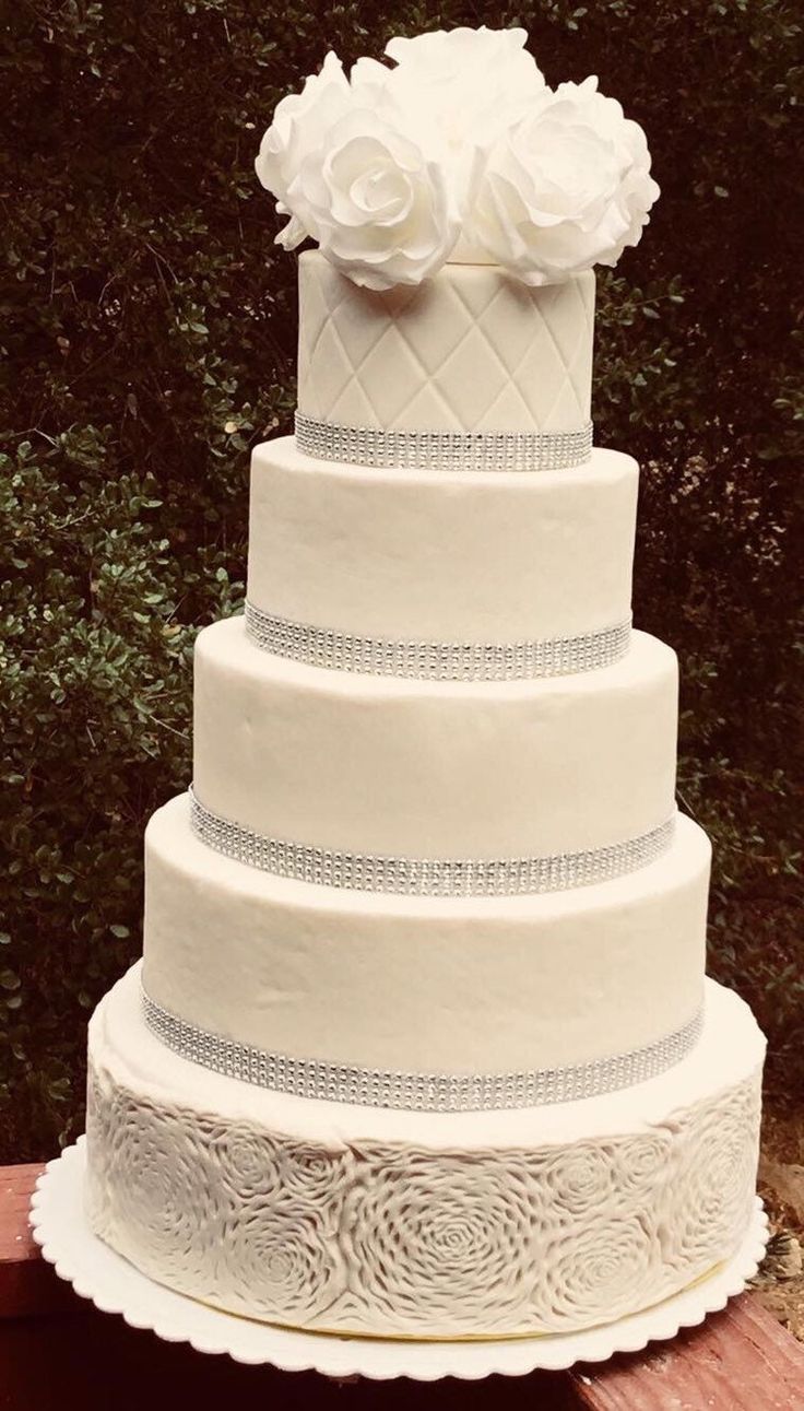 a white wedding cake sitting on top of a wooden table