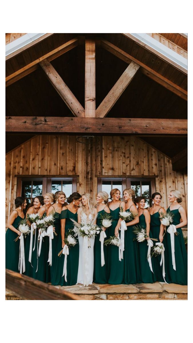 a group of bridesmaids standing in front of a wooden building