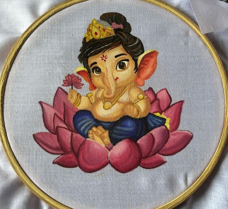 an embroidered picture of a ganeshi sitting on top of a pink flower