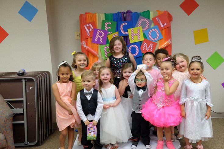 a group of young children standing next to each other in front of a colorful backdrop